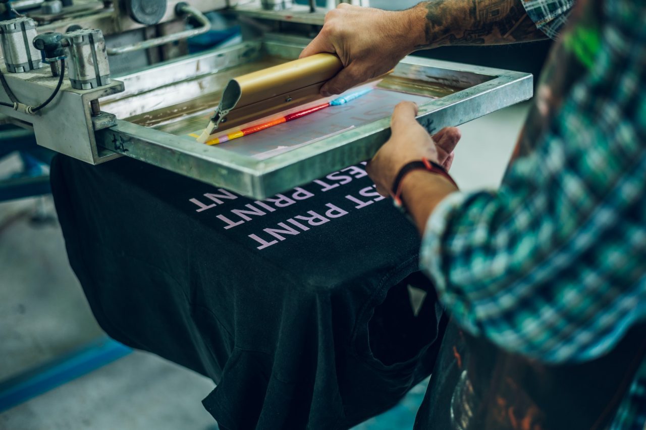 Male Worker Pressing Ink On Frame While Using The Printing Machine In A Workshop 1.jpg